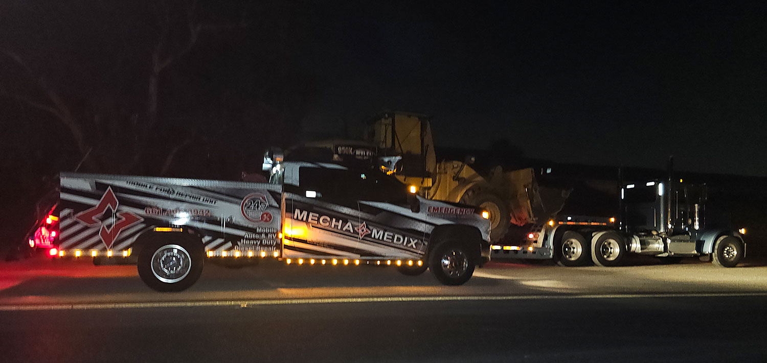 A MechaMedix truck performing diesel engine repair at night